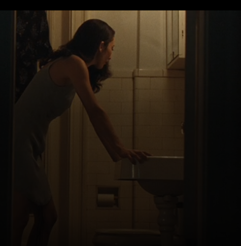 Bathroom scene with Dichen Lachman as Gemma, standing in a bathroom with hands resting on the sink.