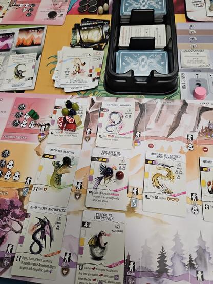 Wyrmspan. A mess of various dragons, eggs, and wooden meat tokens.