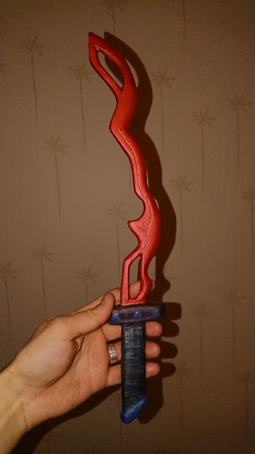 Hand that holds wood dagger that had red/copper blade. And blade is funky.