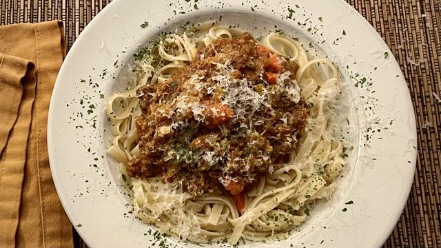 Photo of the dish described in the post: a bowl of pasta with sauce on a white plate. Sprinkled with grated Parmesan and parsley flakes.