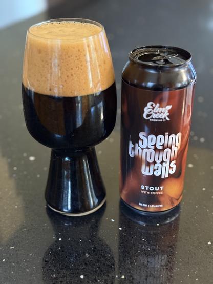 A tall stout glass with a thick dark tan head. The price by can is black with a brown label streaked on shades of brown and tan like coffee creamer blending into a cup of coffee