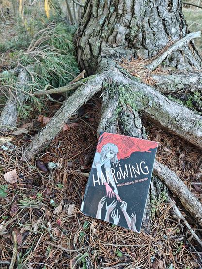Kuvassa The Harrowing -kirjan kansi kuvattuna puun juurakossa.