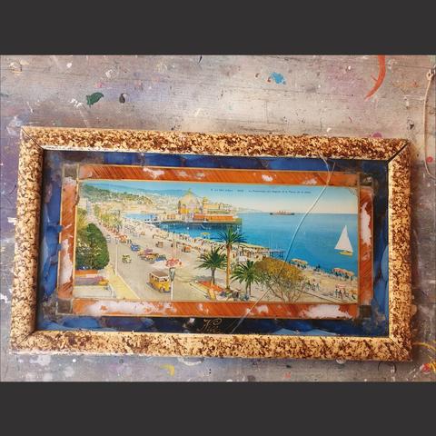 An 1930s souvenir from Nice France featuring a hand coloured print of the Promenade des Anglais in a hand decorated picture frame