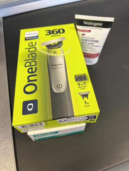 Ein Philips OneBlade und eine Handcreme und Zahnpasta auf dem Kassenband