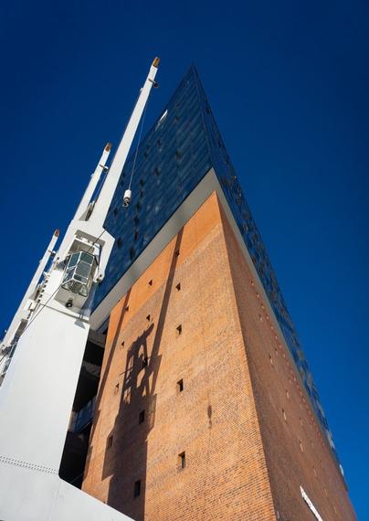 Die Elbphilharmonie in Hamburg ragt majestätisch in den strahlend blauen Himmel. Die moderne Glasfassade trifft auf den historischen Backsteinbau, während ein Kran im Vordergrund das maritime Flair der Hafenstadt unterstreichen.