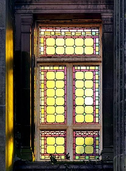 Sunlight streaming through a stained glasa window in an abandoned Victorian  church.
