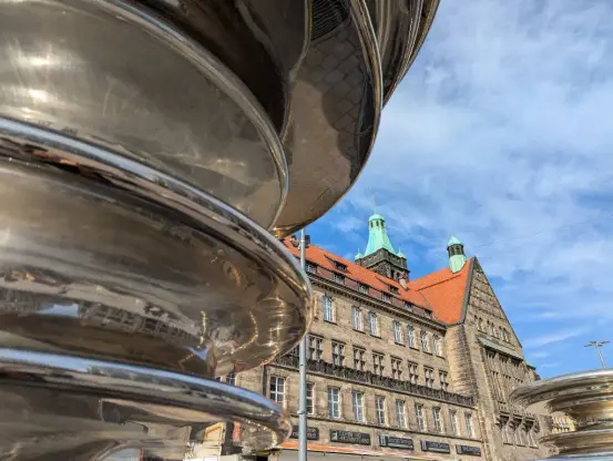 Das Chemnitzer Rathaus, fotografiert mit spiegelnder Skulptur links im Vordergrund