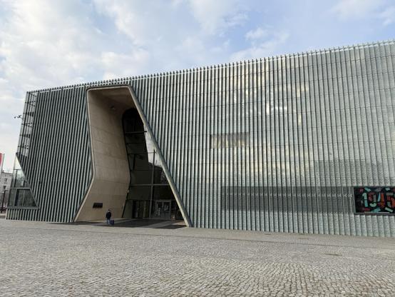 The Polin museum in Warsaw. A modern building featuring a unique, angular facade with vertical glass and concrete elements.
