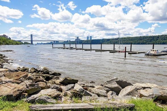 Gazing upon the landscape, a panoramic spectacle unfolds along the majestic Hudson River in the heart of New York City, USA. The focal point of this captivating vista is the iconic George Washington Bridge, an architectural marvel that spans the breadth of the river with commanding grace.