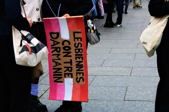 Pancarte "Lesbiennes contre Darmanin" avec un drapeau lesbien