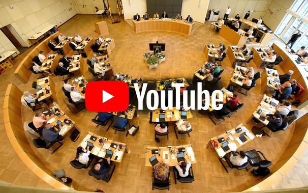 Blick von oben auf den Ratssaal im Stadthaus N1. In der Mitte des Bildes befindet sich das YouTube-Logo.