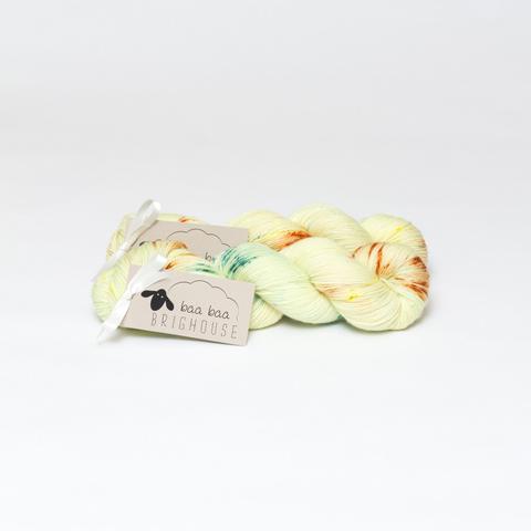 Picture shows two skeins of yarn in shades of lemon with yellow, orange and green speckles.