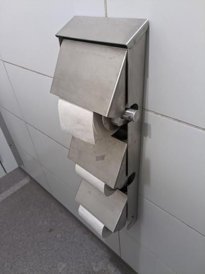 Tre toiletpapirsholdere fastmonteret over hinanden.