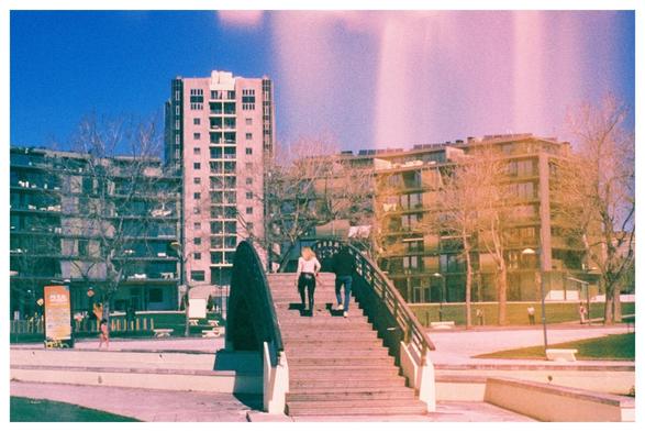 The cityscape of Aveiro. Two people walk on a footbridge over the canal. On the right side of the frame is a light leak.