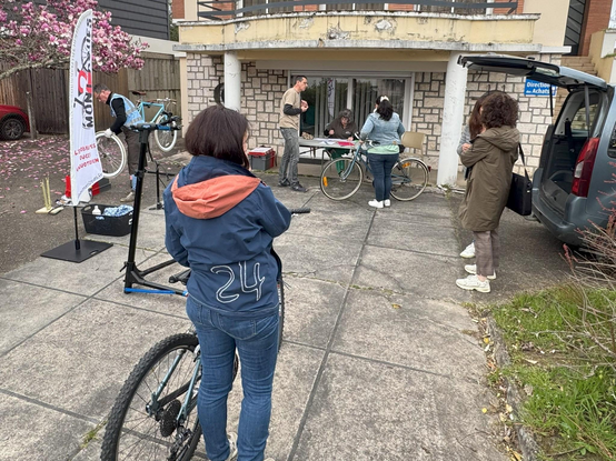 Prestation Objectif Employeur Pro-Vélo, au CHI de Mont-de-Marsan. plusieurs cyclistes qui discutent sur les mobilités. En arrière plan, un technicien de l'association qui démonte une roue pour réparer une crevaison