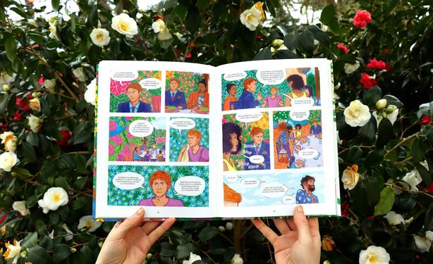 This post follows last week’s one. In this fifth photo, my hands are holding up pages 58 and 59 of the graphic novel Comme une fleur. This scene features a conversation between seven different characters gathered around a restaurant table, set in a region near Pays de la Loire.