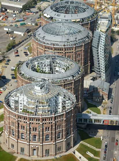 Vier Gasometer von oben fotografiert, in denen sich Wohngebäude befinden.