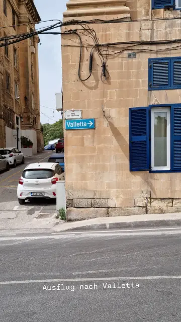 Straßenecke, an der ein Schild mit Pfeil in Richtung Valetta angebracht ist