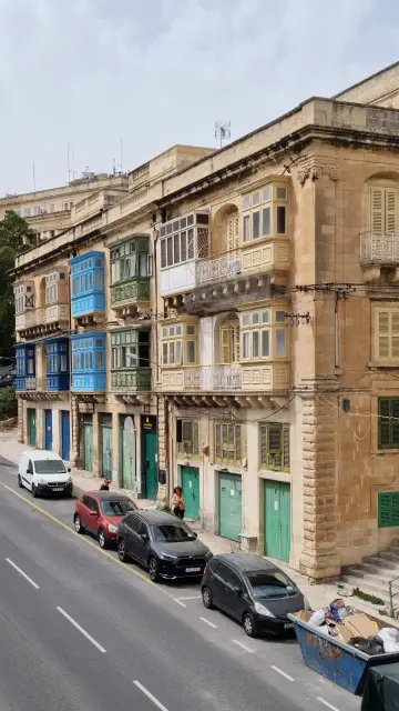 Foto einer Fassade in Valetta mit verschiedenfarbigen geschlossenen Balkonen (Erker). Das ist eine sehr typische Architektur für die Gegend.