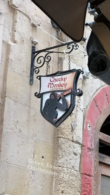 Gezeichnetes Logo des Restaurants "Cheeky Monkey". Es zeigt einen Affen der aus einer Flasche trinkt, die er selbst hält.