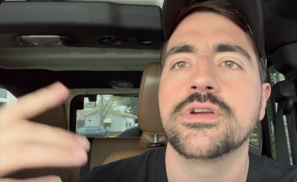 A white man in a baseball cap in his car