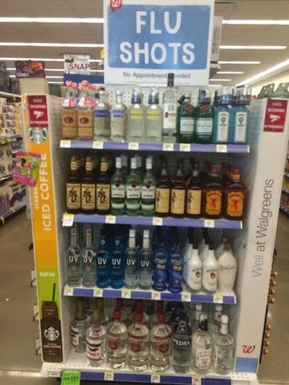 A rack of hard liquors on shelves, below a sign that reads, FLU SHOTS