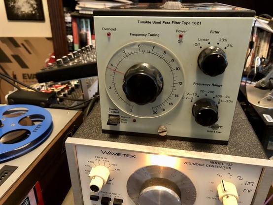 A bruel & kjaer bandpass filter type 1621 sits in a music studoi. It has a square face and is off white. It had three black dials on the face and one switch.
