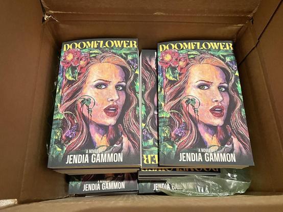 A box filled with copies of the April 8 release by Jendia Gammon, DOOMFLOWER, a horror and sci-fi romcom YA book publishing via Encyclopocalypse Publications.