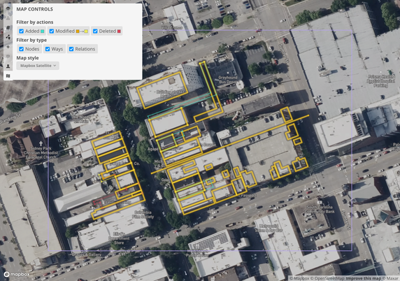 Screenshot of OSMCha visualizing some modified buildings against Mapbox Satellite aerial imagery that shows fewer, much larger buildings from a much more recent date.