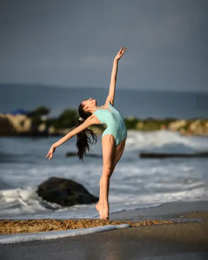 As the first golden rays of sunrise illuminate the shores of Varna, Bulgaria, a ballerina transforms the beach into a breathtaking stage. The soft morning light enhances the elegance of her movements, casting a dreamy glow over the sand and sea. Dressed in a flowing tutu, she dances gracefully along the water’s edge, her delicate pointe work mirroring the gentle waves. The peaceful ambiance of an early summer morning adds to the magic, creating a perfect fusion of ballet and nature. This stunning ballet photoshoot captures the beauty of dance against the serene backdrop of the Black Sea, highlighting the harmony between movement, light, and the coastal landscape. A mesmerizing blend of grace, strength, and the ethereal charm of a seaside sunrise.