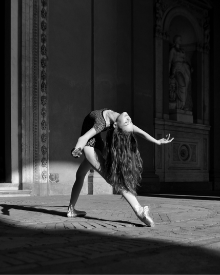 Ballerina Tasya Mudryak showcases her incredible flexibility and elegance in a breathtaking ballet pose at Sanssouci Castle in Potsdam. Wearing a sleek leotard, she blends classical grace with contemporary artistry, creating a striking contrast against the historic beauty of the castle’s architecture. This image captures the harmony between movement and space, where dance transforms a timeless setting into a living work of art.