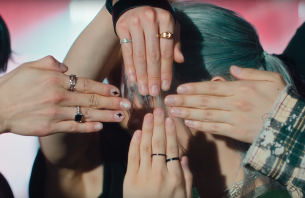 4 hands in front of Felix's face at the beginning of the Chk Chk Boom dance practice video. Top is I.N, right is Seungmin, bottom is Felix, left is Hyunjin. Hyunjin has a manicure with kira kira sparkles on three of the fingers, and an 8-pointed star on the pinky.