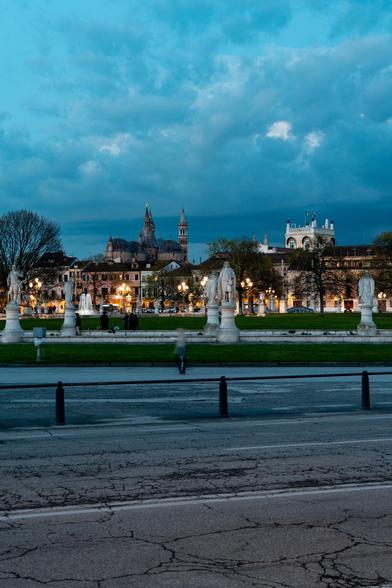 a parc in the blue hour with some statues and old buildings in the background