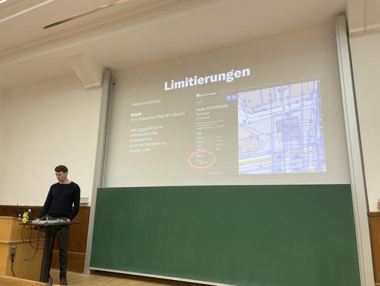 Felix Gündling präsentiert, wie barrierefreies Routing in MOTIS funktioniert. Auf Slide im Hintergrund ist eine OpenStreetMap-Karte mit einem Aufzug dargestellt