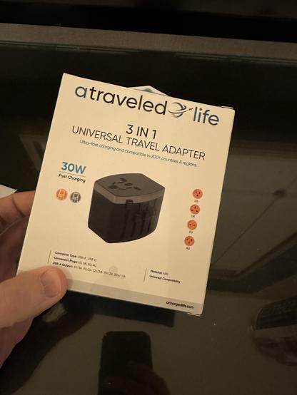 The image shows a packaging box for a 3-in-1 universal travel adapter. It highlights features such as ultra-fast charging, compatibility with over 200 countries, and a 30W output. The bottom includes technical specifications like connector types and plug