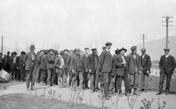 IWW strikers arrested near Savona in April 1912 during the Northern railway construction strike. They are standing outside, uncuffed, with telephone poles and hills in the background.
