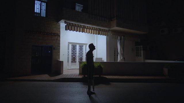 Scène du film. Un jeune homme seul, de nuit, dans une rue.