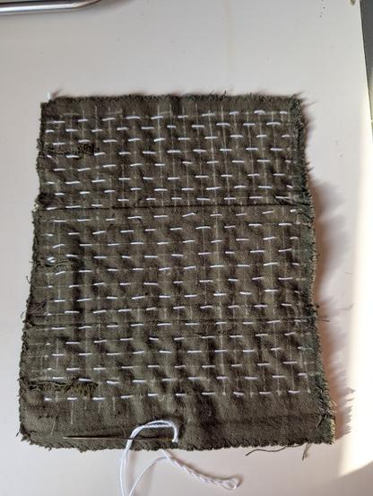 A piece of fabric with sashiko-style embroidery on it in rows of small 5mm stitches