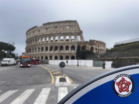 The AntiFascist Fediverse sticker stuck on a sign right in front of the Colosseum, in Rome