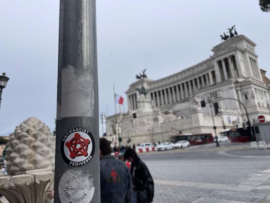 The AntiFascist Fediverse sticker stuck on a pole right in front of Altare Della Patria, in Rome