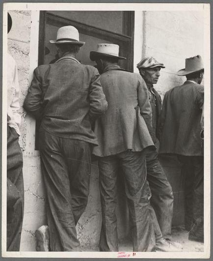 The image depicts a group of men standing in line against the exterior wall of what appears to be an official or institutional building. They are dressed primarily in suits and hats, suggesting that this photo may have been taken during a time when such attire was common for working-class individuals or as part of cultural norms at the start of the 20th century. The men's expressions convey anticipation and patience, possibly waiting to collect their semi-monthly relief checks which indicates they are likely recipients of some form of government aid.

The photograph is in black and white with a monochromatic tone that emphasizes textures such as worn clothing, rough concrete walls, and the stark contrast between light and shadow on the men's figures. This adds to the historical atmosphere of the image. The title "Waiting for the semi-monthly relief checks at Calipatria, California" suggests this photo was taken during a time when unemployment benefits were administered through direct payments or checks, possibly linked to economic difficulties.

Dorothea Lange (1895–1965) is known as an influential photographer who documented significant historical events in the United States. Her works are often associated with capturing moments of social and political relevance during times like The Great Depression. This photograph serves not only as a visual record but also as commentary on economic hardship, societal resilience, and [...]