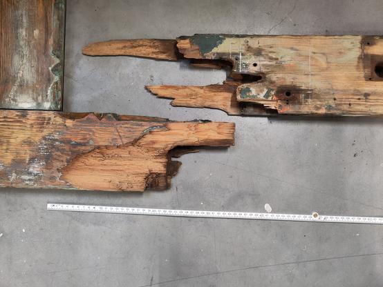 De houten stijl van een poort uit 1900, door midden gebroken.