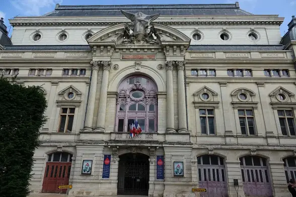 The image depicts a large and ornate building with a grand façade. It features classic architectural elements such as columns, sculptures, and decorative detailing. The entrance has large doors, and there are flags displayed above it. The building appears to be well-maintained and is likely a historical or cultural site. The sky is clear, suggesting a sunny day.

Image Credits: Wikimedia / Gzen92 / CC BY-SA 4.0