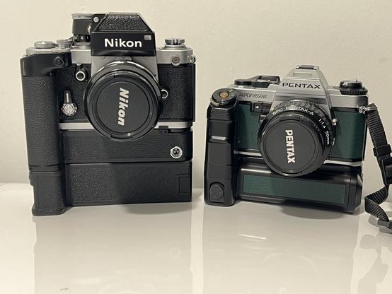 A Nikon f4 with md-3 and battery pack, looking very tall, next to the diminutive super program with motor drive A grip (in green leather).