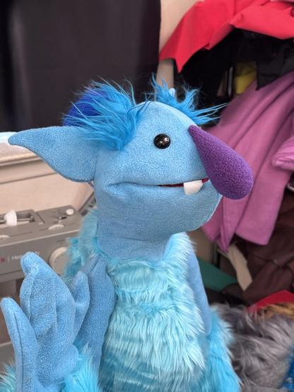 3/4 closed mouth view of a blue ogre live hands puppet with blue topknot and purple nose