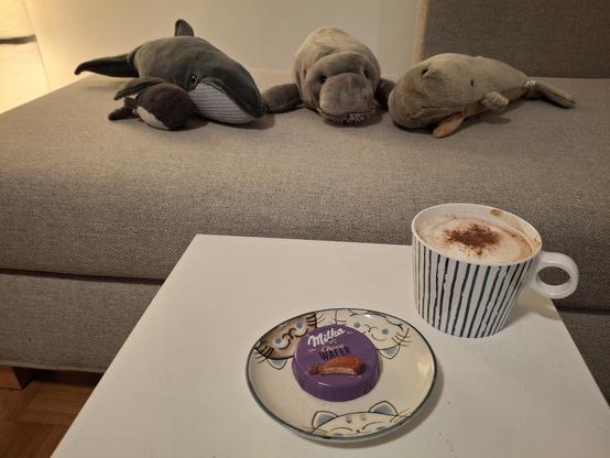 Die Walis und eine Plüschseekuh mit einer Milka Choco Wafer und einer heißen Schokolade mit Milchschaum und Glitzerkakaopulver