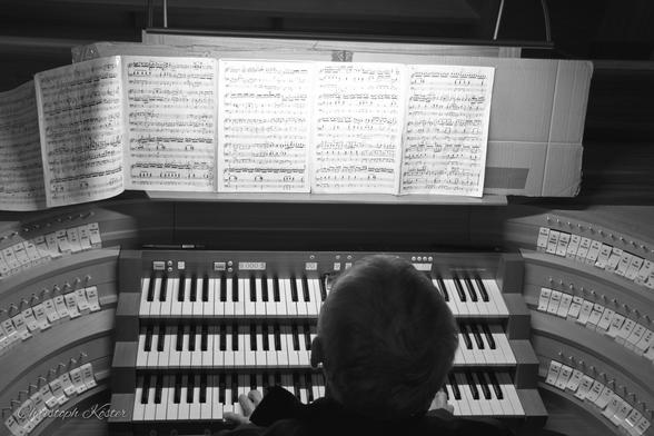 An organist plays a church organ (monochrome picture).