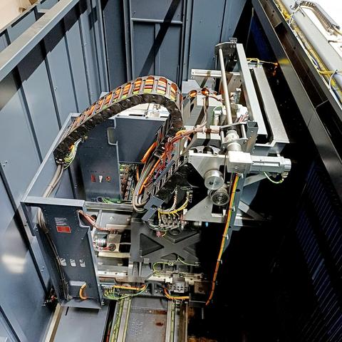 A close-up view of the internal components of the CNC machine, showing complex mechanical parts, wiring, and cable chains. The intricate arrangement of pneumatic and electronic systems supports the precise movement and operation of the machine.