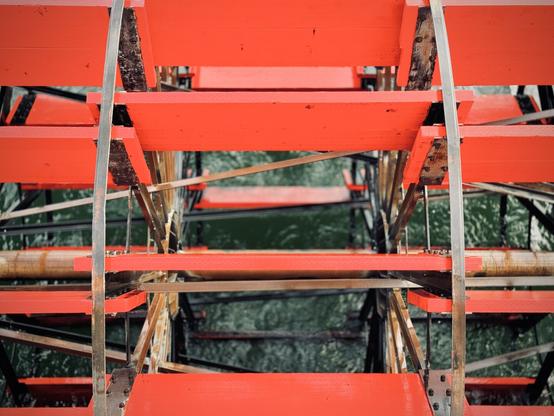 A view through individual planks of wood on the giant red paddle of the Sternwheeler shows it splashing through the dark waters of the Columbia River.