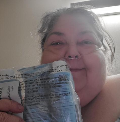 Me with a canula in my nose holding up 3 light blue tubes of Curist 5% lidocaine - forgot to brush my hair haha!